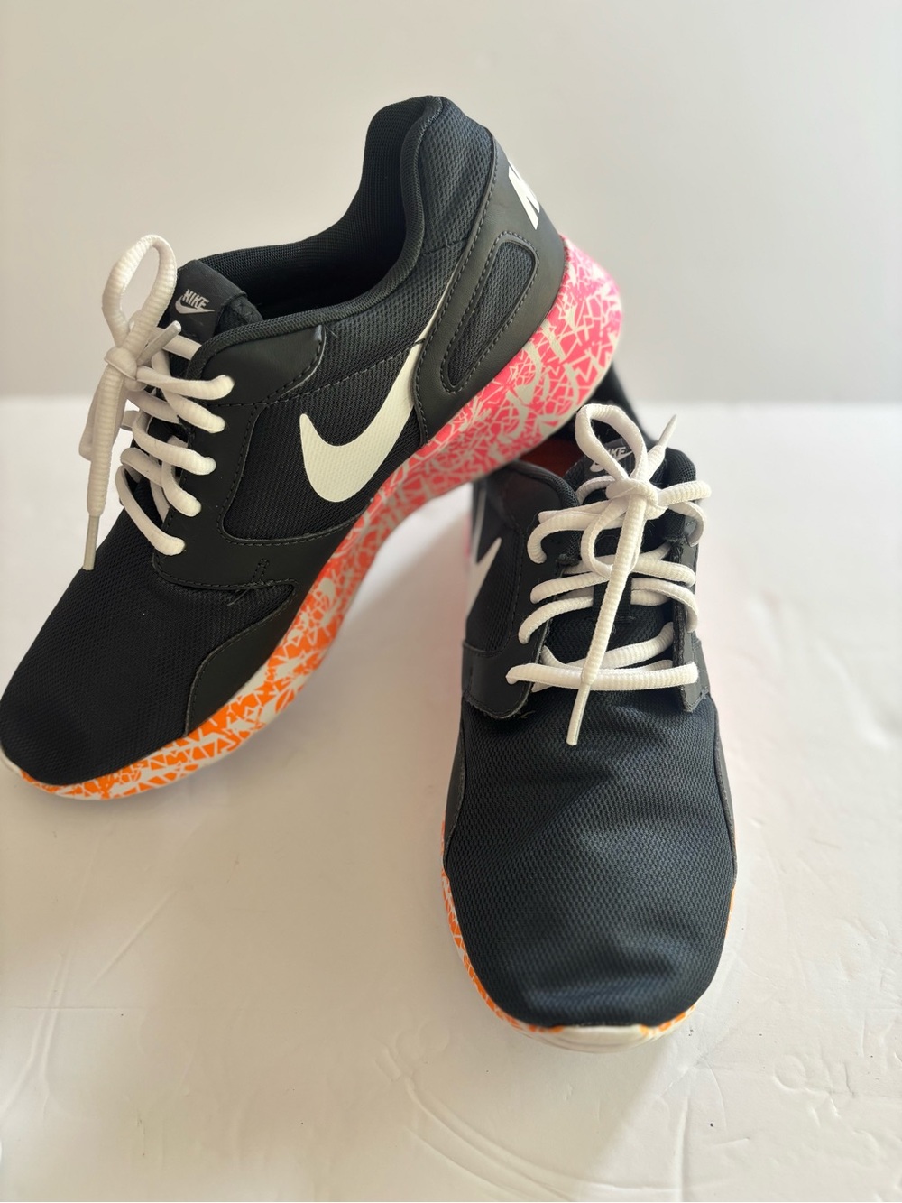 Nike Black Athletic Sneakers with White Swoosh and Pink-Orange Patterned Sole